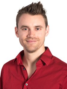 Ben, our Systems Engineer, is wearing a red button-up shirt and smiling towards the camera at an angle.