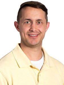 Elias, our Systems Engineer, is facing the camera at an angle, wearing a smile and a yellow ArcSource polo shirt.